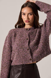 A young woman is wearing a cropped, button-up sweater with a textured, speckled pattern in shades of purple, pink, and gray.